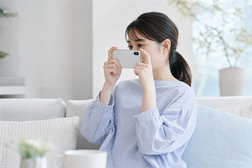 ご自宅でスマートフォンを構えているところ