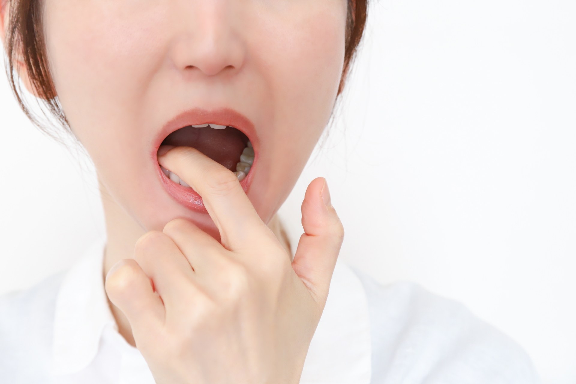 奥歯の銀歯を気にして口元を指で確認する女性